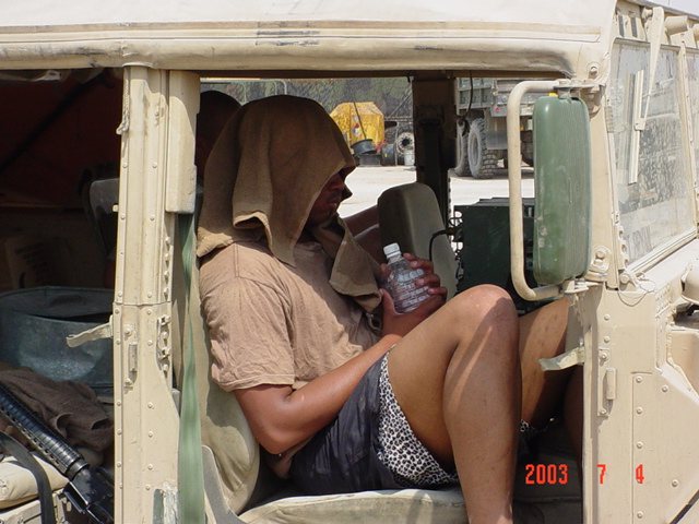 Beating the heat with a wet towel in the cab of a truck, July 4, 2003.