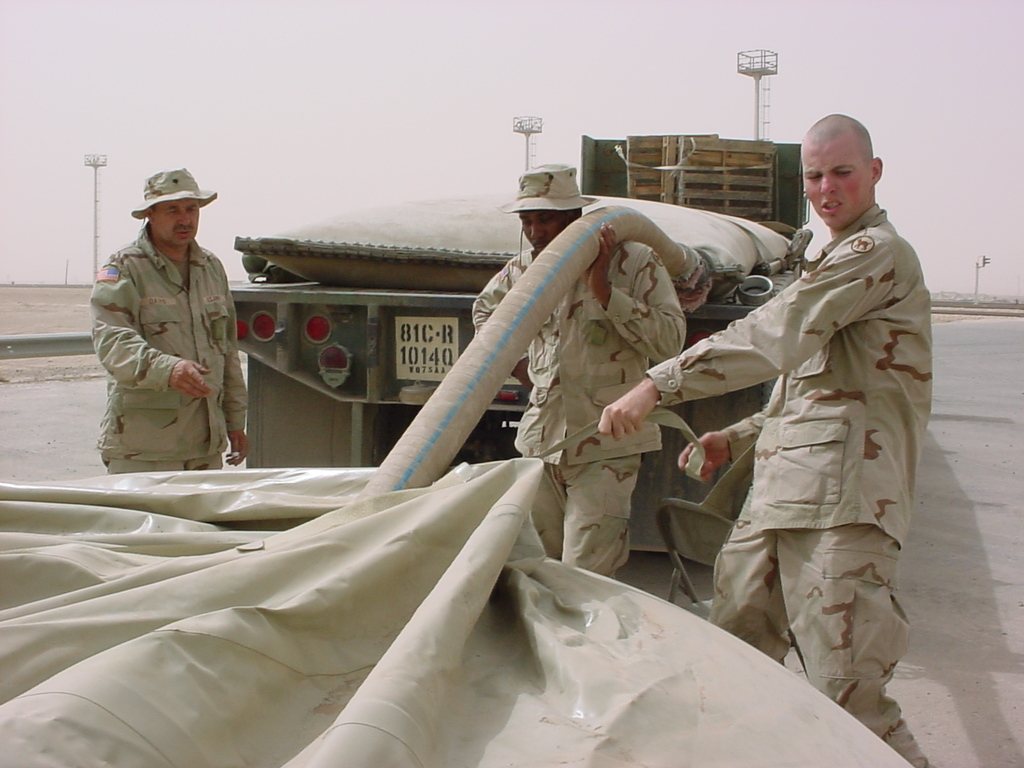 1014th Quartermaster Company soldiers handle a fuel hose at a collapsible fuel bladder, May 2003.